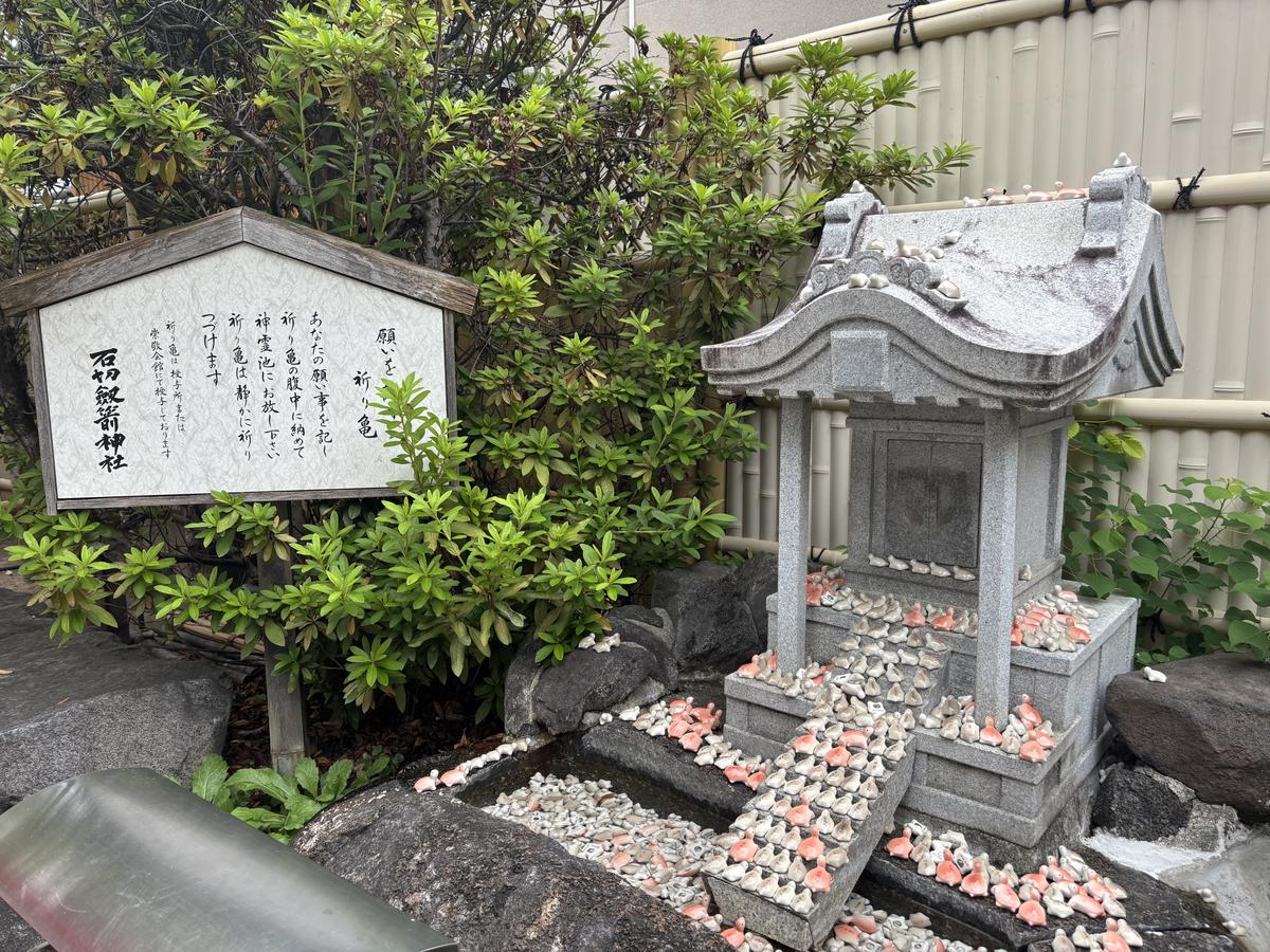 祈り亀の説明板と、陶器の亀が並ぶ祠
